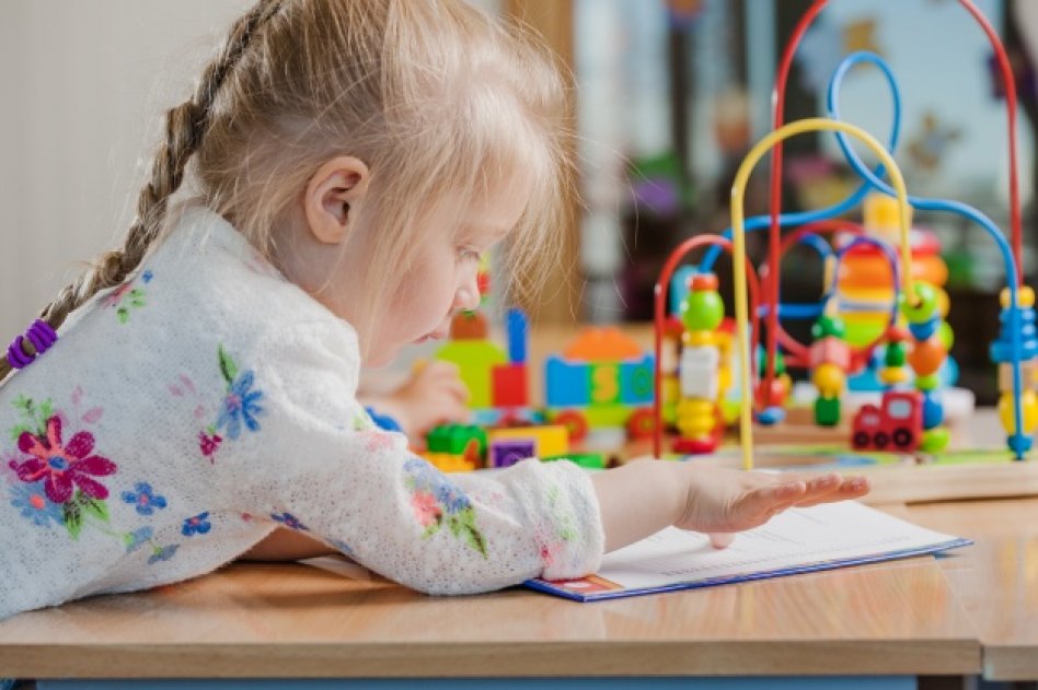 Dans une salle de jeux Une petite fille joue en passant son doigt sur une feuille de papier.