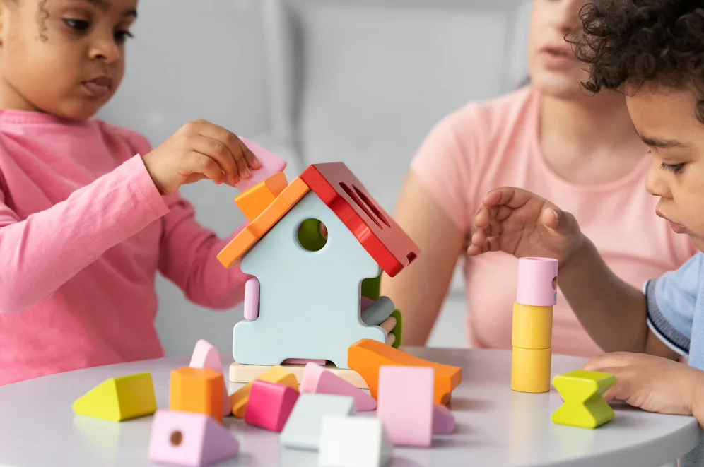 Deux petits enfants accompagnés de leur éducatrice s'adonnent à une activité d'apprentissage ludique .