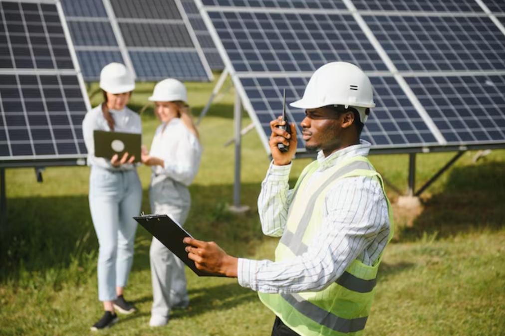 Formation sur le terrain – deux apprentis installent des panneaux solaires sous la supervision d'un technicien..